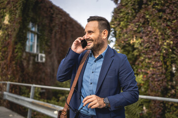 Adult businessman stand on the terrace and talk on mobile phone