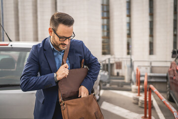 businessman stand in the parking lot and put stuff in his briefcase