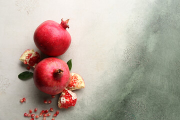 Fresh ripe pomegranates with seeds and leaves on grunge background