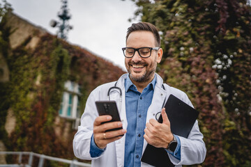 man doctor hold clipboard and use cellphone stand on the terrace