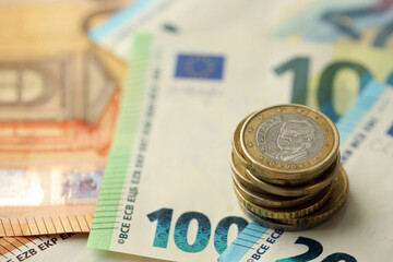 One euro coin lies on huge amount of different euro dollars banknotes