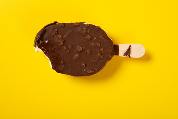 a chocolate outer popsicle with a bite on yellow background