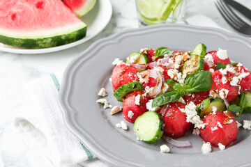 Delicious watermelon salad with feta cheese, vegetables and spices on white table, closeup