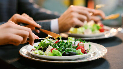 Healthy Menu. Closeup Of Unrecognizable Couple Eating Greek Salad At Dinner In Restaurant And Drinking Champaigne, Crop