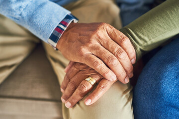 Senior people, compassion and support with holding hands, assistance or grief in nursing home. Elderly couple, hope and bonding as empathy in living room for love, care or communication in retirement