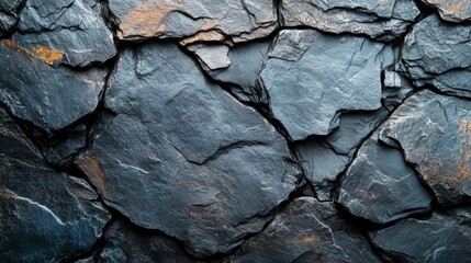 Fototapeta premium A close-up view reveals a textured slate stone wall displaying various shades of gray alongside subtle rust accents under natural light. The stones interlock beautifully, showcasing unique patterns.