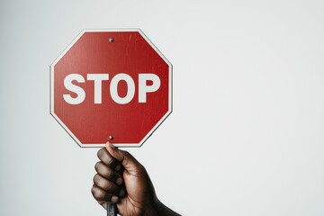 A hand holds a stop sign against a simple background, signaling the need to pause and be cautious