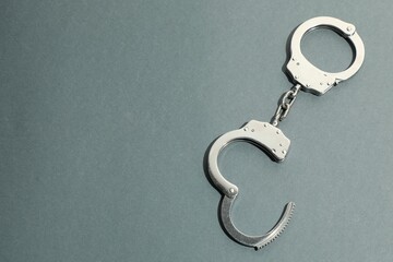 Classic chain handcuffs on grey background, top view. Space for text