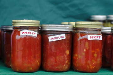 Retro glass jars of homemade salsa at a farmers market.