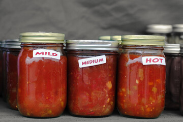 Retro glass jars of homemade salsa at a farmers market.
