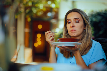 Woman Eating a Salad Disliking the Taste and Texture. Restaurant customer finding the food bad and repulsion
