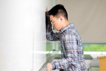 A student leans against a the classroom wall whiteboard giving up