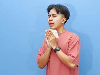 Unhealthy young man holding tissue, preparing to sneeze, expressing sadness and pain, isolated on...