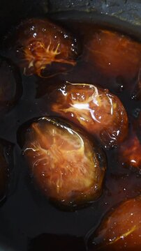 close-up shot of ambarella or june plum jam marmalade with wooden spoon, tropical sweet flavored dessert covered with sugar syrup, slow motion in 60fps vertical orientation
