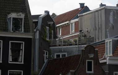 Variety of top floor windows and roofs in building sating tight to each other  - 2