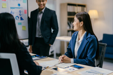 Young asian businesswoman is listening to a presentation by her colleague in a modern office. The...