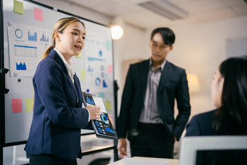 Confident businesswoman leads productive meeting, presenting detailed plan with graphs. Diverse team discusses strategies for success