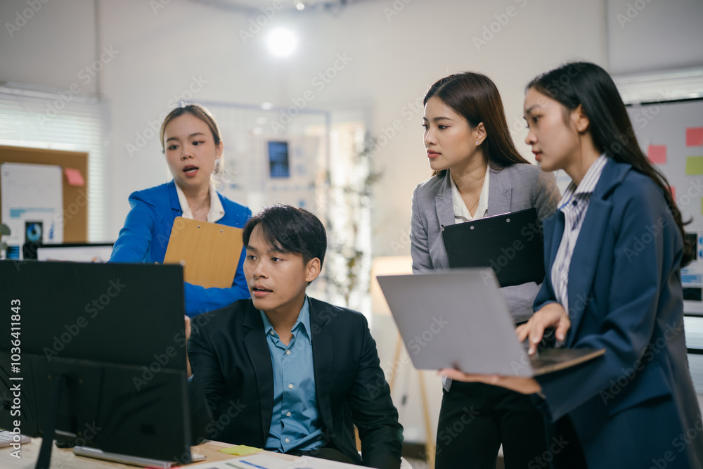 Poster team of young asian professionals are having a discussion while reviewing data on a computer screen.