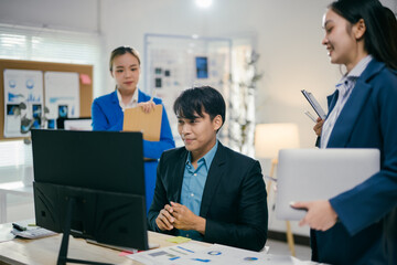 Diverse team of asian businesspeople in a modern office. Engaged in a lively meeting using a computer for discussions about an exciting new project. Showcasing collaboration. Teamwork. Confidence