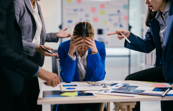 Businesswoman is feeling stressed while her coworkers are being aggressive and blaming her for something during a business meeting
