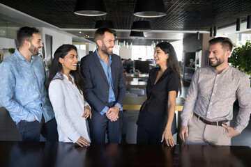 Cheerful diverse young business colleagues enjoying successful teamwork, standing together in...