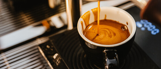 Espresso pouring from coffee machine at cafe,Brewing the espresso coffee from the machine warm tone