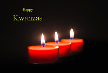 Happy Kwanzaa image: Traditional african american ethnic holiday design concept with three burning candles on black background.