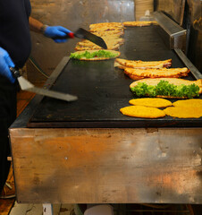 chef with gloves cooking piadinas stuffed with sliced ​​cold cuts, cheese and lettuce cooked on a hot cast iron plate, a typical dish from Italy