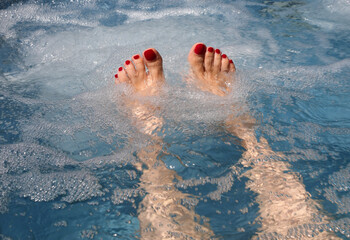 feet with red nail polish surrounded by thousands of tickling and massaging air bubbles in a...