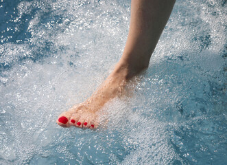 foot with red nail polish in hydromassage full of many bubbles