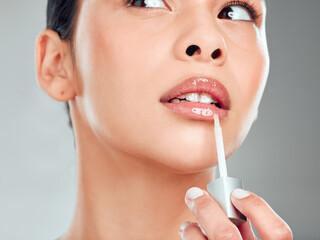 Makeup, glow and cosmetics with lipgloss of woman in studio for lips, moisturizer and aesthetic....