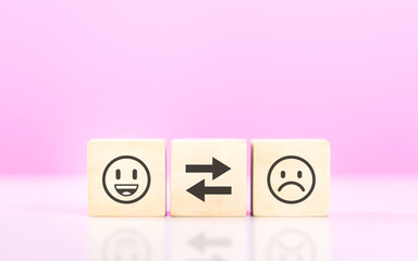 A Wooden blocks featuring smiley and sad face stickers, symbolizing the concept of choosing between...