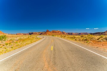 Empty road with majestic cliffs in the background. Canyonlands National Park, Utah