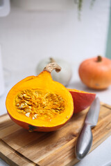 A freshly cut pumpkin, beautifully halved, is resting on a cutting board alongside a knife