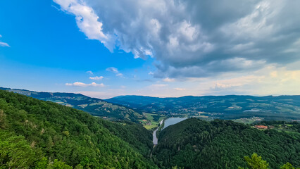 Fototapeta premium Breathtaking aerial view from Geierwand of alpine lake Stubenbergsee in Stubenberg, Styria, Austria. Surrounded by lush green forests and rolling hills of East Styrian Hill Country in Austrian Alps