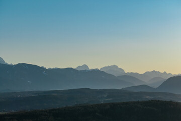 Fototapeta premium Scenic sunset view of majestic mountain peak Jof Montasio in Julian Alps seen from Sternberg, Wernberg, Carinthia, Austria. Valley covered by idyllic forest in Austrian Alps. Tranquil alpine landscape