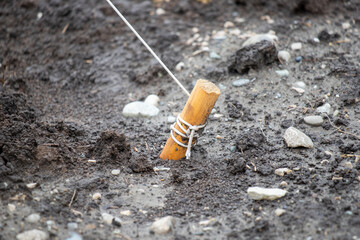 Wooden peg in the ground with a white rope.