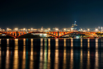 Communal bridge over the Yenisei River at night with beautiful lighting and reflection in the water