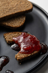 Rustic Bread with Berry Jam on Black Plate on white background