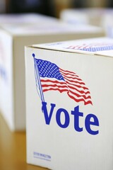 Ballot boxes with U.S. flags and voting signs on the blurry background of the voting hall