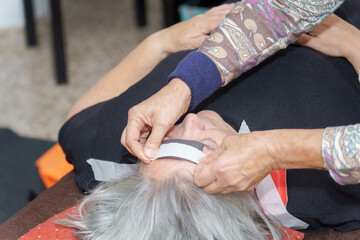 a therapist places a magnet on a patient's head during a biomagnetism session.