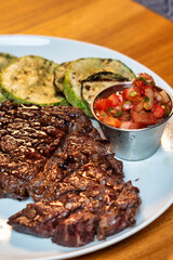 Indulge in a Delicious Grilled Steak Accompanied by Fresh Vegetables and Tangy Salsa