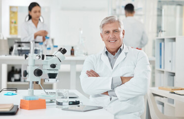 Laboratory, portrait and mature man with confidence, smile and medical science innovation. Healthcare, happy face and scientist at desk with arms crossed, study or pride in pharmaceutical engineering