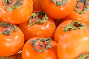 Delicious ripe persimmons in bowl on blurred background, closeup