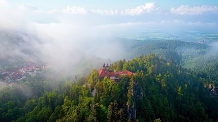 A medieval castle perched on a mountaintop with fog swirling around it.
