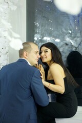 A young couple in a room decorated for Christmas or New Year.