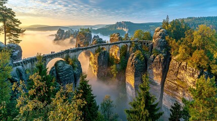 A stone bridge connects two towering rock formations in a scenic mountain landscape. The bridge is covered in mist and the sky is filled with clouds.