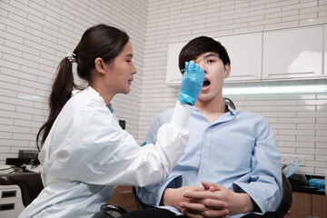 Asian female dentist examine young male patient teeth and toothache stomatology in dental clinic,...