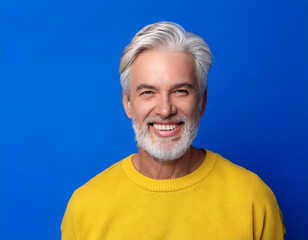Obraz premium Portrait of Mature Handsome Man Happily Smiling Against Blue Studio Background