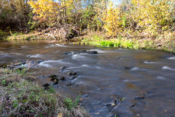 fast river between stones, stream of water passes the stone, ecology in the river, beautiful natural environment as background, blurred stream of water